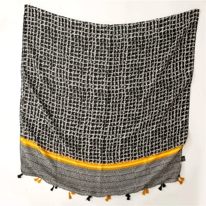Close-up of geometric grid scarf featuring yellow contrast stripes and handmade tassels