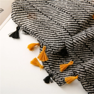 Detailed view of striped scarf with soft crinkle texture and vibrant yellow fringe tassels
