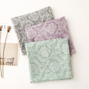 Detailed view of gray, purple, and mint green scarves with baroque damask print and frayed edges