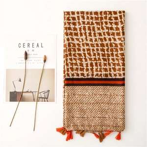 Detail of retro geometric grid scarf featuring orange and brown tassels and cotton texture