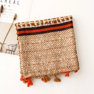 Detail of geometric pattern scarf with red stripes and tassels on linen fabric