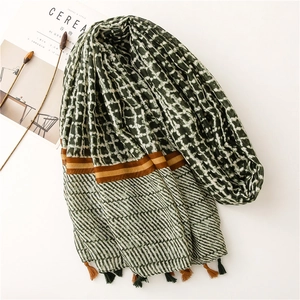 Detail of dark green grid patterned long scarf with tassels and soft fabric texture