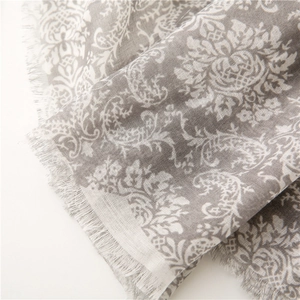 Detail shot of vintage paisley print scarf featuring fringe edges and soft grey texture