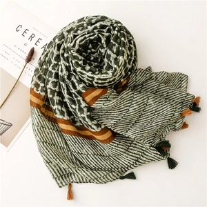 Macro detail of scarf showing dark green geometric patterns and soft tassel edges