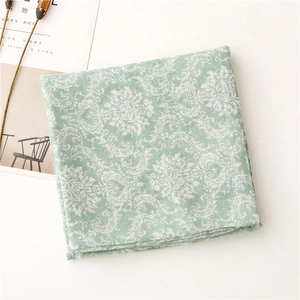 Detail of light green floral scarf featuring damascus patterns and delicate frayed edges