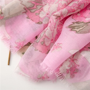 Detail of pink floral scarf showing breathable fabric texture and natural fringed edges