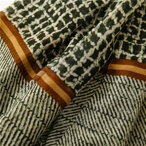 Detailed macro view showing the textured linen fabric and geometric patterns of the scarf