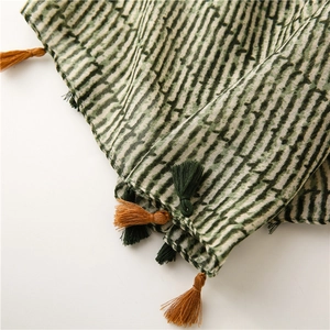 Detailed close-up of green and white striped scarf with bicolor orange tassels