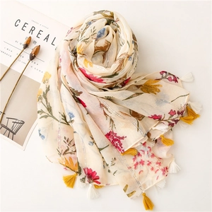 Detail view of floral scarf with beige base and colorful flower patterns and tassels
