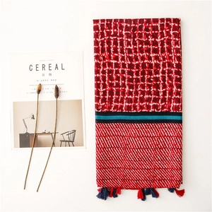 Detailed view of red and white plaid scarf with striped patterns and colorful tassels