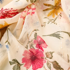 Detail of floral printed scarf with silver sequin threads on beige translucent fabric