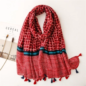 Detailed view of red and white plaid scarf with fringe and geometric stripe patterns