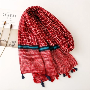 Detailed macro view of vibrant red plaid scarf with decorative tassels and cotton-linen texture