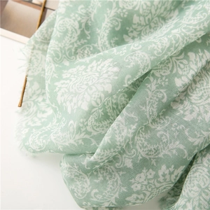 Close-up of light green floral pattern scarf with natural fringe edges and soft texture