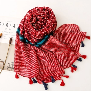 Detailed view of red and white printed scarf with tassels next to a lifestyle magazine