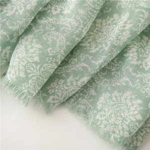 Close-up of light green floral scarf with damascus patterns and frayed edge detail