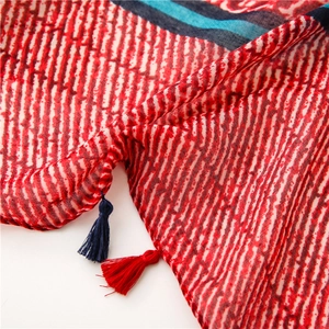 Detailed close-up of geometric scarf patterns with decorative red and blue fringe tassels