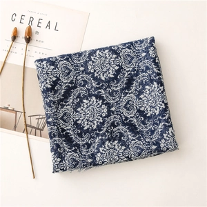 Detail of vintage blue paisley cotton linen scarf with frayed edges beside a magazine