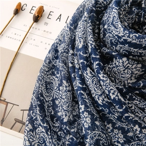 Close-up of blue cotton linen scarf with white paisley pattern and woven texture