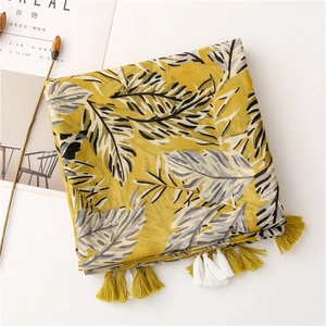 Détail d'écharpe jaune à motif de feuilles de bananier avec glands bicolores