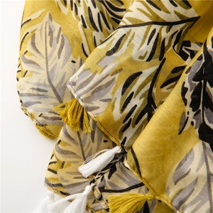 Détail de l'écharpe à motif de feuilles tropicales avec franges jaunes et texture coton