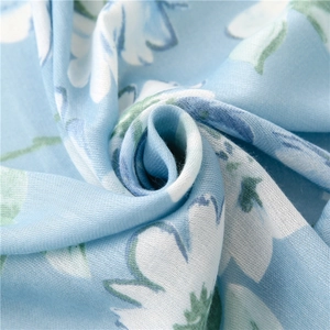 Dettaglio ravvicinato del tessuto azzurro della sciarpa con eleganti stampe floreali