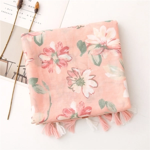 Dettaglio di una sciarpa a fiori rosa con eleganti nappe lunghe su sfondo minimalista