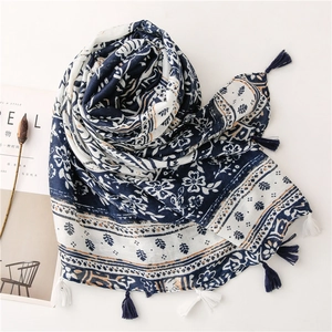 Detail of blue and white porcelain floral scarf with elegant fringe tassels and linen texture