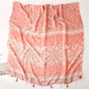 Detail of coral pink bohemian scarf featuring floral prints and fringed tassel edges