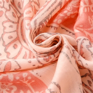Macro detail of bohemian floral print scarf with soft woven texture and orange patterns