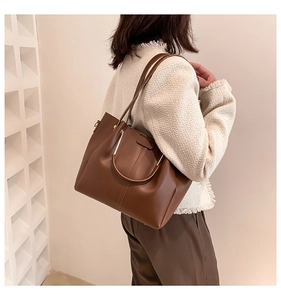 Détail du sac cabas vintage en cuir marron foncé avec anse dorée et bandoulière