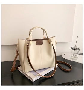 Détail du sac seau crème avec poignée dorée et bandoulière marron élégant