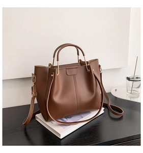 Détail d'un sac cabas vintage marron foncé avec ferrures dorées sur un magazine
