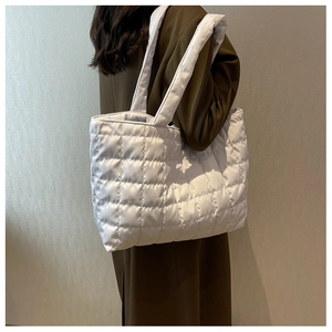 Detailed view of the white quilted tote bag featuring a soft padded puffer grid texture