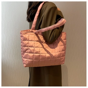 Side view of pink quilted tote bag with diamond stitching on a model's shoulder
