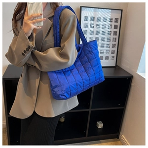 Chic blue quilted puffer tote bag shown on model in a modern professional setting