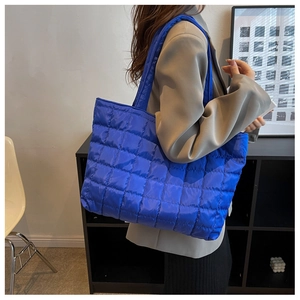 Detail of bright blue quilted tote bag in shiny nylon with wide shoulder strap