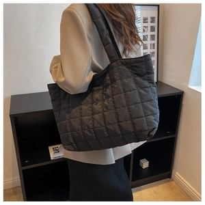 Detail of a black quilted tote bag with large capacity and elegant rhombus pattern
