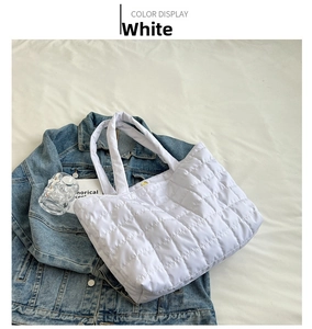 Detail of white quilted tote bag with large square stitching on denim fabric background