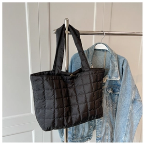 Detailed view of the black quilted texture and padded handle on a large tote bag