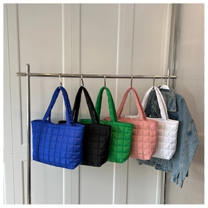 Quilted tote bags in blue, black, green, pink, and white hanging on a metal rack