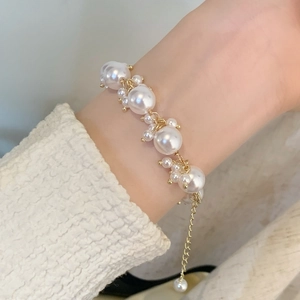 Elegant multi-size white pearl bracelet with gold adjustable chain on a model's wrist