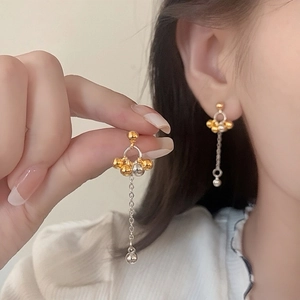 Élégantes boucles d'oreilles pendantes à boules bicolores portées par un mannequin chic