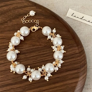 Close-up of handmade pearl bracelet with gold wire wrap and adjustable lobster clasp detail