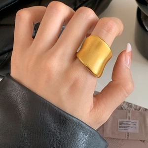 Bague large minimaliste en or mat avec texture brossée sur le doigt d'une femme