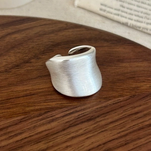 Gros plan détaillé d'une bague large ouverte en argent brossé sur fond en bois
