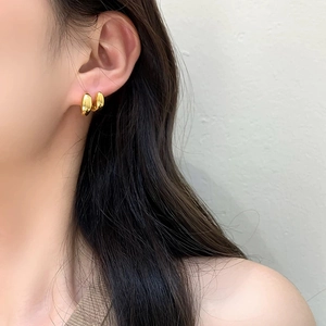 Boucles d'oreilles dorées en forme de U polies portées par un mannequin style épuré