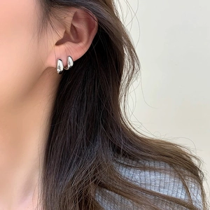Gros plan de boucles d'oreilles argentées polies en forme de haricot portées par un mannequin