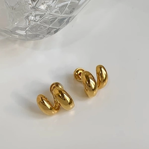 Gros plan de boucles d'oreilles créoles C torsadées dorées avec une finition miroir polie