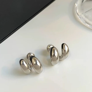 Vue macro de boucles d'oreilles argentées géométriques au fini poli et design double arc